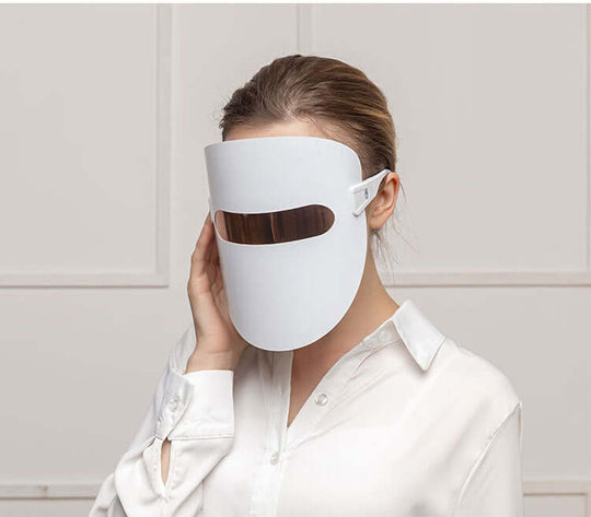 A woman wearing a beauty LED light face therapy mask 