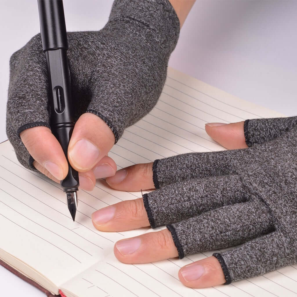 A woman wearing copper arthritis compression gloves writing in a notebook